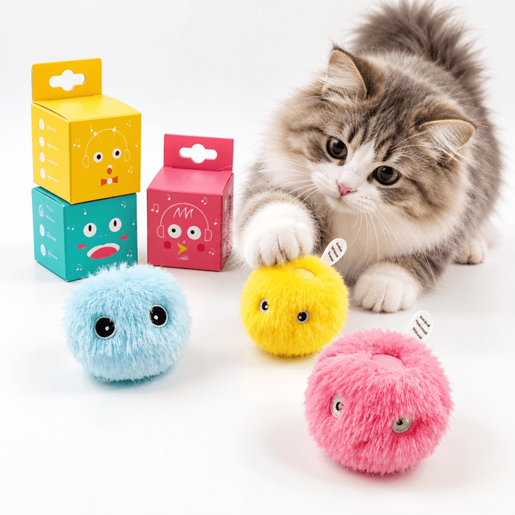 Cat Furry Hunting Balls shown as blue, yellow and pink fluffy toy balls with cartoon eyes beside a curious kitten